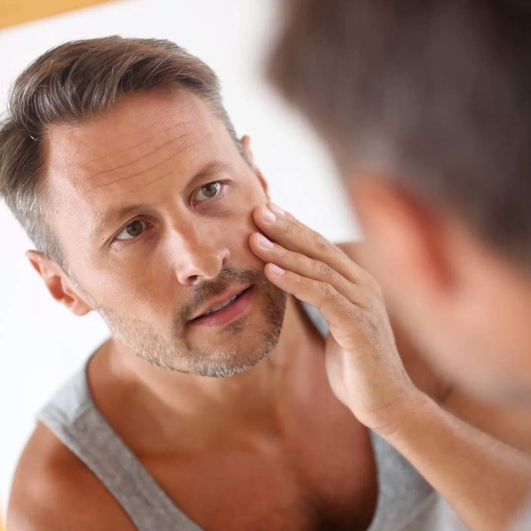 Man looking at the damage of time in a mirror